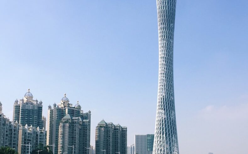 a very tall tower towering over a city next to a river