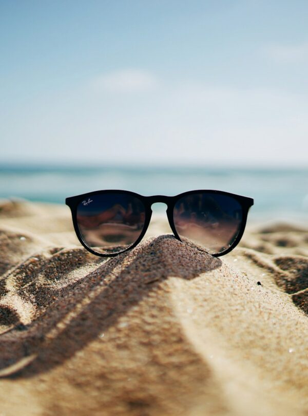 black Ray-Ban Wayfarer sunglasses on beach sand