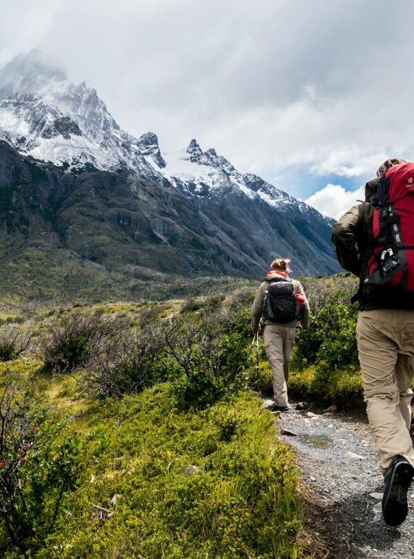 two person walking towards mountain covered with snow