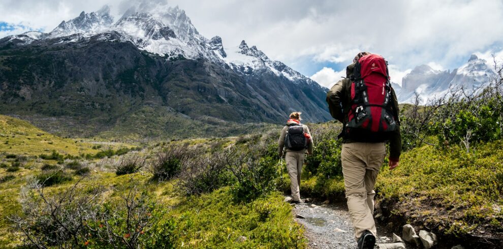 two person walking towards mountain covered with snow